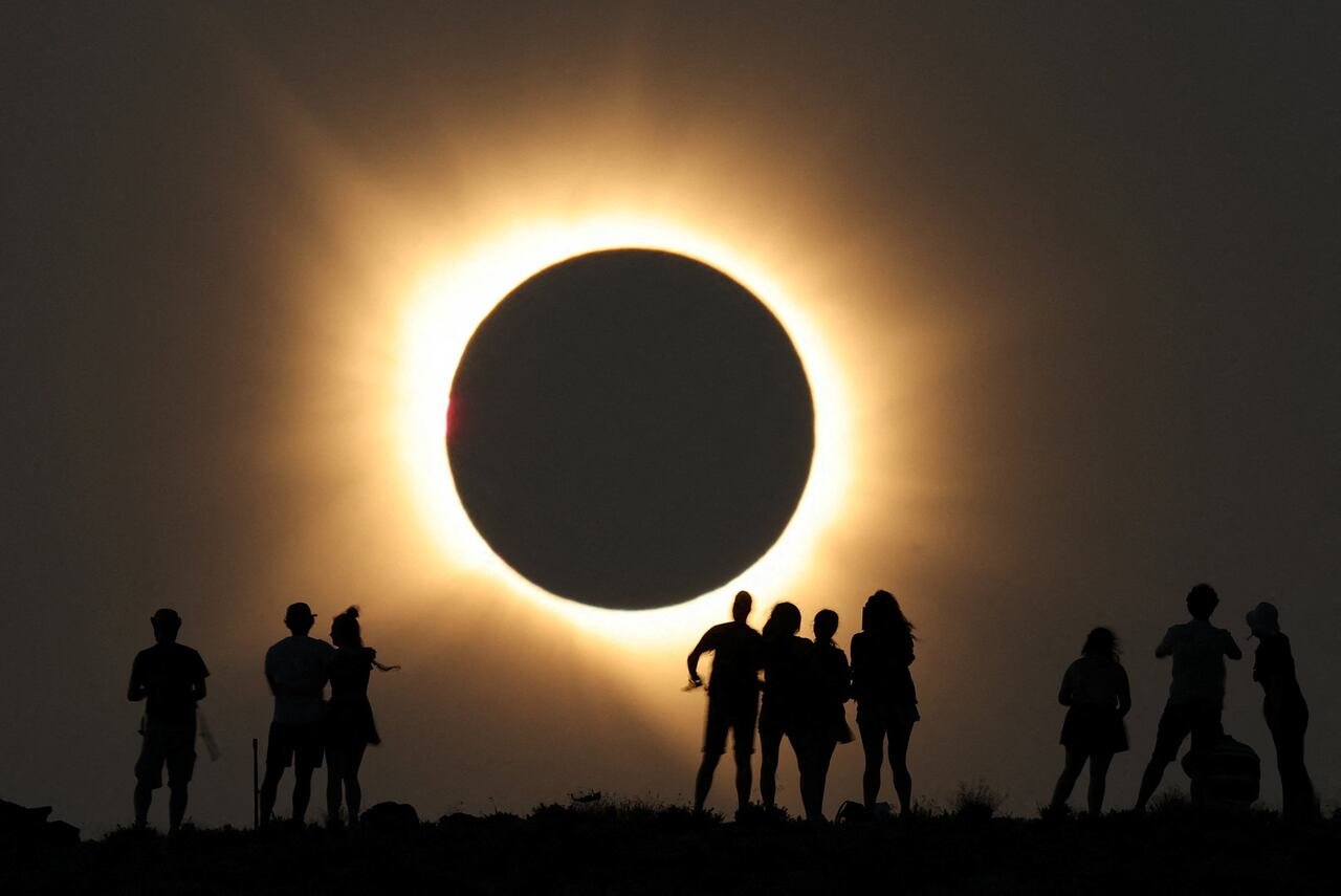 default-374 People in silhouette outside an observatory with a total solar eclipse in the distance.